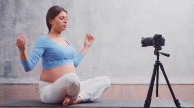 Genç hamile bir kadın yoga egzersizleri ve meditasyonla ilgili bir video bloğu hazırlıyor. Etkilenen kişi bir kameraya video veya akış kaydeder.