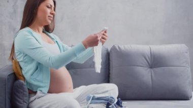 Genç hamile kadın evde dinleniyor ve bebek bekliyor. Hamilelik, annelik, sağlık ve yaşam tarzı kavramı.