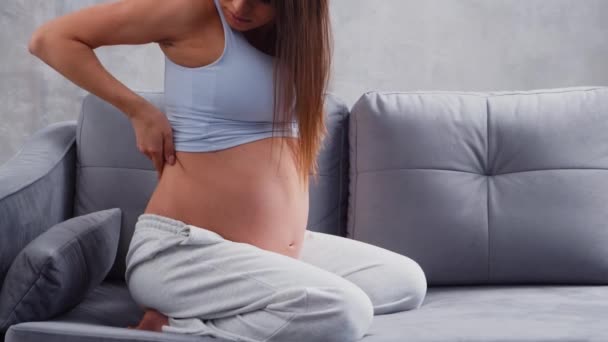 Молодая беременная женщина страдает от болей в спине. Концепция беременности, материнства, здоровья и образа жизни. — стоковое видео