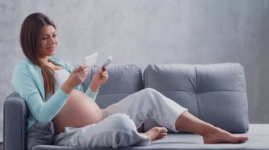 Genç hamile kadın evde dinleniyor ve bebek bekliyor. Hamilelik, annelik, sağlık ve yaşam tarzı kavramı.