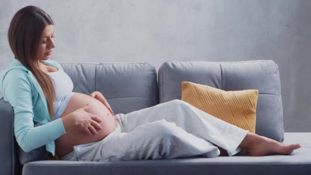 La giovane donna incinta sta riposando a casa e aspetta un bambino. Il concetto di gravidanza, maternità, salute e stile di vita. — Video Stock