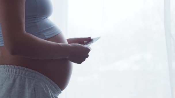 Молодая беременная женщина отдыхает дома и ждет ребенка. Концепция беременности, материнства, здоровья и образа жизни. — стоковое видео