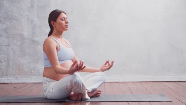Giovane donna incinta che fa esercizi di yoga e medita a casa. Il concetto di salute, consapevolezza, relax e benessere. — Video Stock