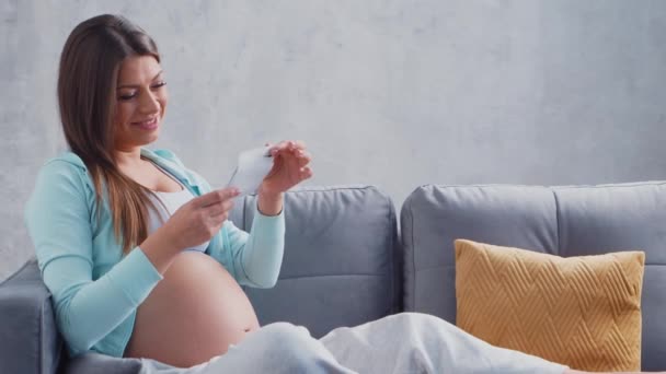 La giovane donna incinta sta riposando a casa e aspetta un bambino. Il concetto di gravidanza, maternità, salute e stile di vita. — Video Stock