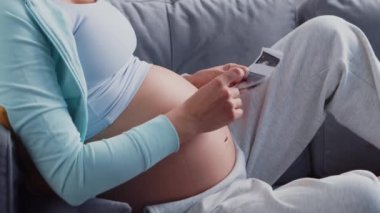 Genç hamile kadın evde dinleniyor ve bebek bekliyor. Hamilelik, annelik, sağlık ve yaşam tarzı kavramı.