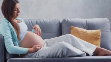 Genç hamile kadın evde dinleniyor ve bebek bekliyor. Hamilelik, annelik, sağlık ve yaşam tarzı kavramı.