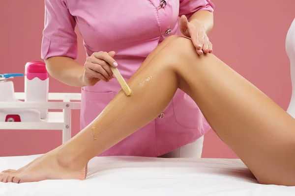 Kosmetikerin entfernt junge weibliche Körper und Beine mit heißem Wachs. Die Frau hat eine Schönheitsbehandlung. Depilation, Epilation, Haut- und Gesundheitskonzepte. — Stockfoto