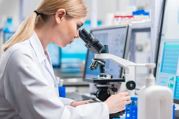 Professionele vrouwelijke wetenschapper werkt aan een vaccin in een modern wetenschappelijk onderzoekslaboratorium. Genetische ingenieur werkplek. Toekomstige technologie en wetenschap. — Stockfoto