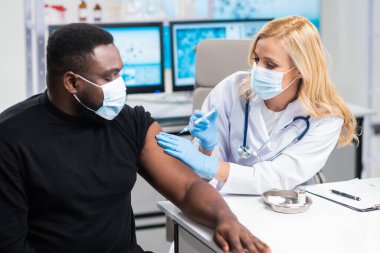 Profesyonel doktor şırınga ve şırınga kullanarak koronavirüs aşısı yapıyor. Hastane ofisinde profesyonel tıp çalışanı ve hasta. Aşı ve güvenlik.