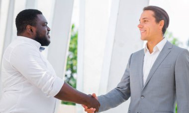 Finans, iş ve işbirliği konsepti. İki başarılı iş adamı sokakta konuşuyor. Ofis çalışanları iş meselelerini dışarıda tartışıyorlar..