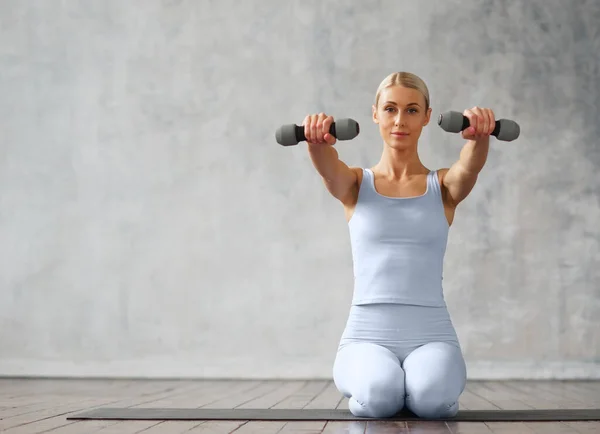 Joven mujer rubia delgada en ropa deportiva se dedica a la aptitud en casa. Concepto de deporte, salud y estilo de vida. — Foto de Stock