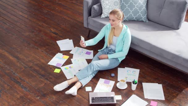 La jeune femme tient une conférence par vidéoconférence alors qu'elle est assise par terre à la maison. Étudiante, entrepreneure ou pigiste travaillant ou étudiant à distance. Le concept d'enseignement à distance et d'emploi. — Video