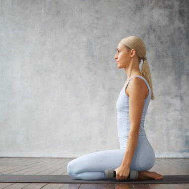 Spor giyimli genç, narin sarışın kadın evde fitness yapıyor. Spor, sağlık ve yaşam tarzı konsepti.