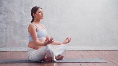 Genç hamile kadın yoga yapıyor ve evde meditasyon yapıyor. Sağlık, farkındalık, rahatlama ve sağIık kavramı.