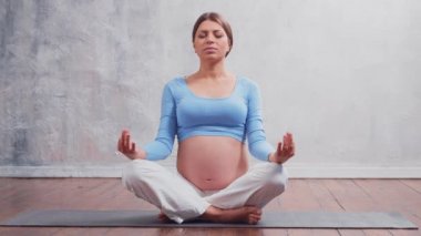 Genç hamile kadın yoga yapıyor ve evde meditasyon yapıyor. Sağlık, farkındalık, rahatlama ve sağIık kavramı.