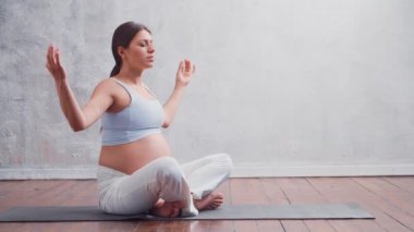 Genç hamile kadın yoga yapıyor ve evde meditasyon yapıyor. Sağlık, farkındalık, rahatlama ve sağIık kavramı.