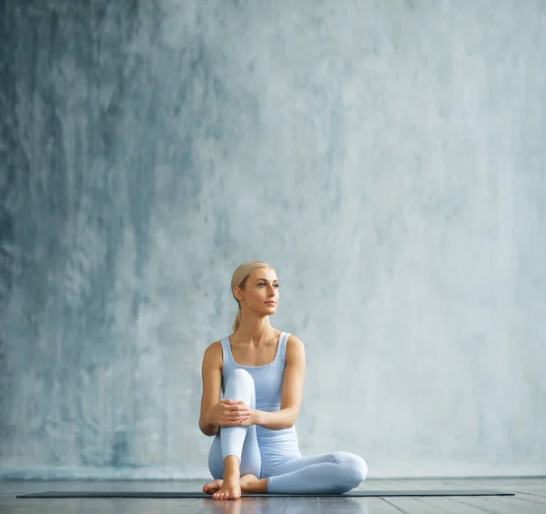 Mulher loira esbelta jovem em sportswear envolve-se na aptidão em uma sala de treinamento espaçosa. Esporte, saúde, ginástica e estilo de vida conceito. — Fotografia de Stock