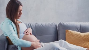 Genç hamile kadın evde dinleniyor ve bebek bekliyor. Hamilelik, annelik, sağlık ve yaşam tarzı kavramı.