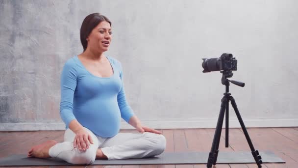 Een jonge zwangere vrouw maakt een vlog over zwangerschap. De influencer neemt video 's of streams op op een camera op. — Stockvideo