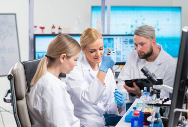 Profesyonel bilim adamları modern bir bilimsel araştırma laboratuvarında bir aşı üzerinde çalışıyorlar. Genetik mühendisliği işyeri. Gelecekteki teknoloji ve bilim.