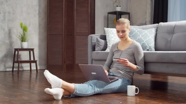 Fiatal nő megrendeli áruk online egy laptop és egy hitelkártya. Online vásárlási, szállítási és fizetési rendszerek koncepciója. — Stock videók