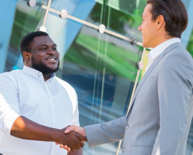 Finans, iş ve işbirliği konsepti. İki başarılı iş adamı sokakta konuşuyor. Ofis çalışanları iş meselelerini dışarıda tartışıyorlar..