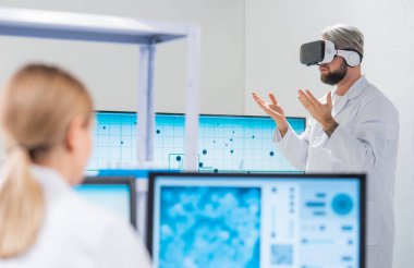 Genetik mühendisleri Sanal Gerçeklik teknolojisini kullanıyorlar. Profesyonel bilim adamları modern bir bilimsel araştırma laboratuvarında bir aşı üzerinde çalışıyorlar. Geleceğin bilimi.
