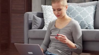 Genç bir kadın internetten dizüstü bilgisayar ve kredi kartıyla mal sipariş ediyor. Çevrimiçi alışveriş, dağıtım ve ödeme sistemleri kavramı.