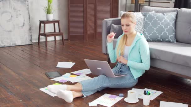 Mujer joven tiene video llamada reunión conferencia mientras está sentado en el suelo en casa. Estudiante, empresaria o freelancer que trabaja o estudia a distancia. Concepto de aprendizaje a distancia y empleo. — Vídeos de Stock