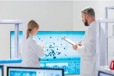Profesyonel bilim adamları modern bir bilimsel araştırma laboratuvarında bir aşı üzerinde çalışıyorlar. Genetik mühendisliği işyeri. Gelecekteki teknoloji ve bilim.