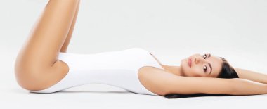 Beyaz iç çamaşırlı, çekici ve ince esmer kız stüdyoda poz veriyor. Sağlıklı yaşam tarzı, spor ve vücut bakımı kavramı.