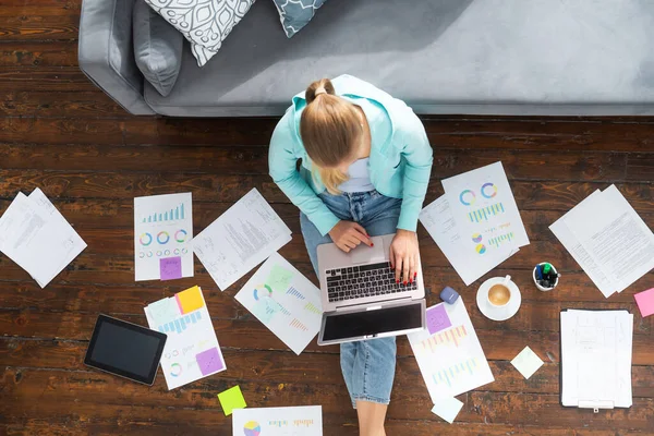 Junge Frau arbeitet mit Laptop mit Dokumenten, während sie zu Hause auf dem Boden sitzt. Studentin, Unternehmerin oder Freiberuflerin, die aus der Ferne über das Internet arbeitet oder studiert. — Stockfoto