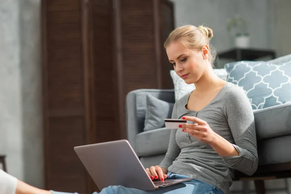 Νεαρή γυναίκα παραγγέλνει αγαθά online χρησιμοποιώντας ένα φορητό υπολογιστή και μια πιστωτική κάρτα. Έννοια συστημάτων ηλεκτρονικής αγοράς, παράδοσης και πληρωμής. — Φωτογραφία Αρχείου