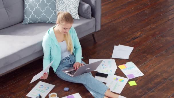 Egy fiatal nő laptoppal dolgozik, miközben otthon ül a padlón. Diák, vállalkozó vagy szabadúszó lány, aki távolról dolgozik vagy tanul. A távoktatás és a foglalkoztatás fogalma. — Stock videók