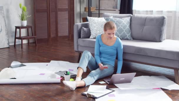 Молодая женщина работает с документами, используя ноутбук, сидя дома на полу. Студентка, предприниматель или девушка-фрилансер, работающая или обучающаяся дистанционно. Концепция дистанционного обучения и работы. — стоковое видео