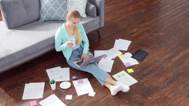 若い女性は自宅の床に座っている間、ノートパソコンを使用して文書で動作します。学生、起業家やフリーランスの女の子がリモートで働くか勉強します。距離学習と仕事の概念. — ストック動画