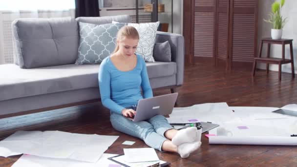 Mladá žena pracuje s dokumenty pomocí notebooku, zatímco sedí doma na podlaze. Studentka, podnikatelka nebo na volné noze pracující nebo studující na dálku. Koncept distančního vzdělávání a práce. — Stock video