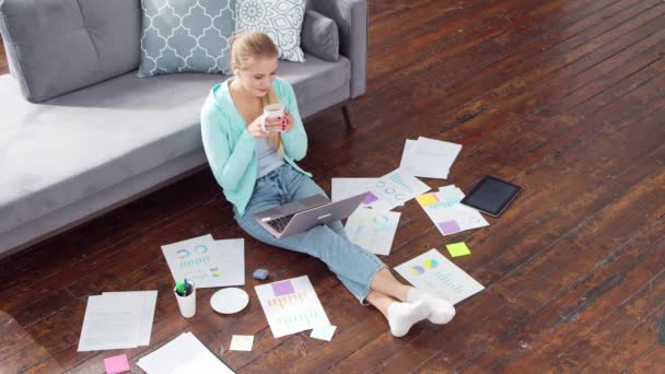 La jeune femme travaille avec des documents à l'aide d'un ordinateur portable alors qu'elle est assise sur le sol à la maison. Étudiante, entrepreneure ou pigiste travaillant ou étudiant à distance. Le concept d'enseignement à distance et d'emploi. — Video