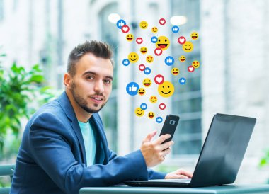 Genç başarılı bir yazar ya da blogcu sosyal ağ haberlerini izler, beğeni ve görüşlerini animasyon emojisi şeklinde alır. Sosyal medya, internet ve çevrimiçi iletişim kavramı.