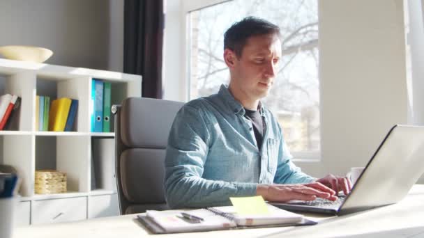 Young male entrepreneur works at home office at the computer. Workplace of freelancer or student. Remote work and education concept. — Stock Video