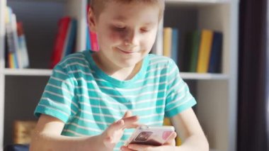 Çocuk Masa 'da ödevini yapıyor. Şirin Çocuk, Akıllı Telefon Cihazı ve Okul Eğitim Kitapları 'nın yardımıyla Evde Öğreniyor. Çalışma ve Eğlence Konsepti .