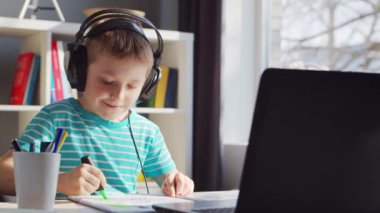 Çocuk Masa 'da ödevini yapıyor. Şirin Çocuk Laptop Bilgisayar ve Okul Ders Kitapları 'nın yardımıyla Evde Öğreniyor. Eğitim ve Uzaktan Eğitim Konsepti.