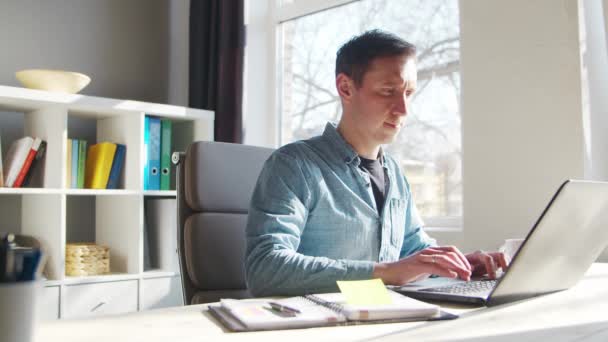 Fiatal férfi vállalkozó dolgozik otthon iroda a számítógép. Szabadúszó vagy diák munkahelye. Távmunka és oktatási koncepció. — Stock videók