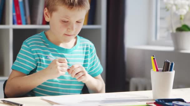De jongen doet zijn huiswerk aan de tafel. Schattig kind is thuis leren met behulp van lesboeken en schoolmaterialen. Studie en onderwijs Concept. — Stockvideo