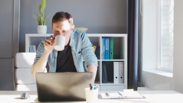 Joven empresario masculino trabaja en la oficina en casa en la computadora. Lugar de trabajo del freelancer o estudiante. Trabajo remoto y concepto de educación. — Vídeo de stock