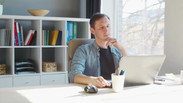Jeune entrepreneur masculin travaille au bureau à domicile à l'ordinateur. Lieu de travail de pigiste ou d'étudiant. Concept de télétravail et d'éducation. — Video