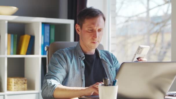 Jeune entrepreneur masculin travaille au bureau à domicile à l'ordinateur. Lieu de travail de pigiste ou d'étudiant. Concept de télétravail et d'éducation. — Video