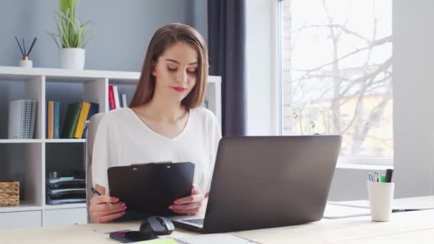 젊은 여성은 가정 사무실에서 컴퓨터를 사용 한다. 여성 사업가, 프리랜서, 학생들의 직장. 원격 작업 과 교육 개념. — 비디오