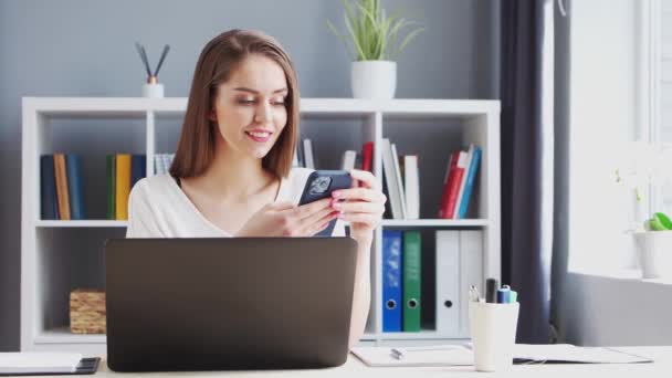 Mujer joven trabaja en el Ministerio del Interior usando computadora y Smertphone. Lugar de trabajo de Emprendedora, Freelancer o Estudiante. Trabajo remoto y concepto de educación. — Vídeos de Stock