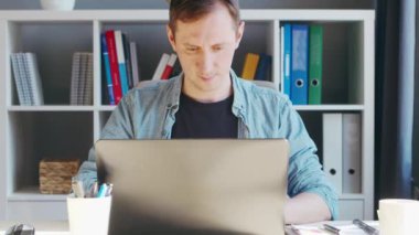 Genç erkek girişimci bilgisayarın merkez ofisinde çalışıyor. Serbest çalışan ya da öğrencilerin çalıştığı yer. Uzak çalışma ve eğitim kavramı.